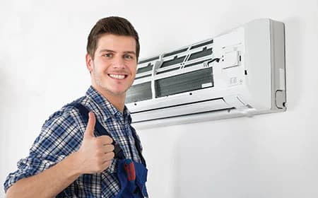 Technician beside an open wall-mounted AC